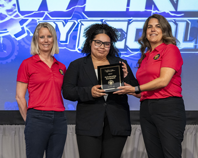 A student poses with their award plaque between two NBCOT staff members