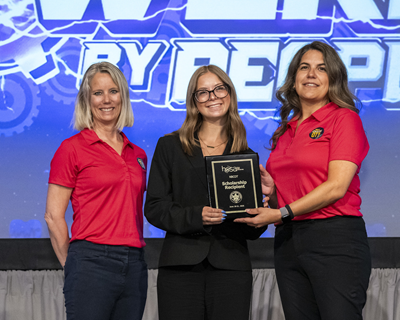 A student poses with their award plaque between two NBCOT staff members