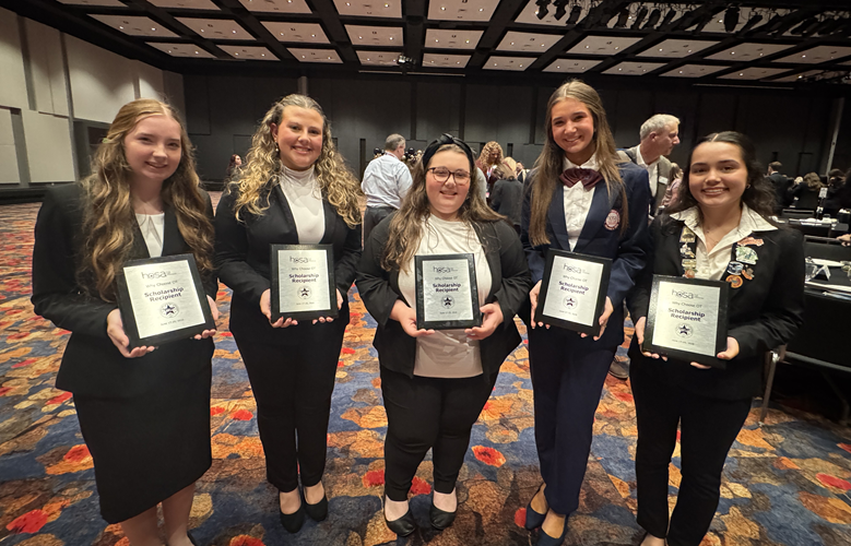 Five young women stand together, each holding a plaque.