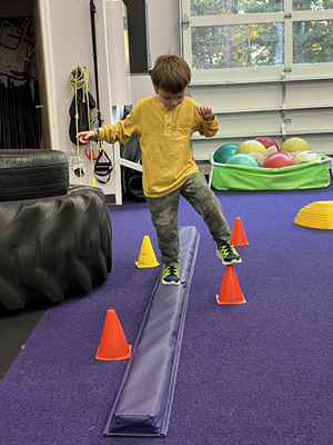A child walks on a low balance beam.