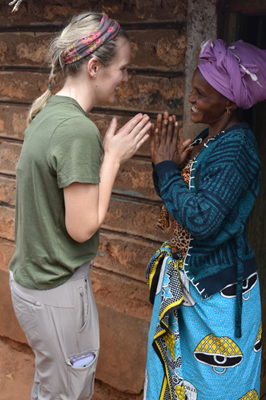Two women face each other with their hands in a prayer hands gesture.