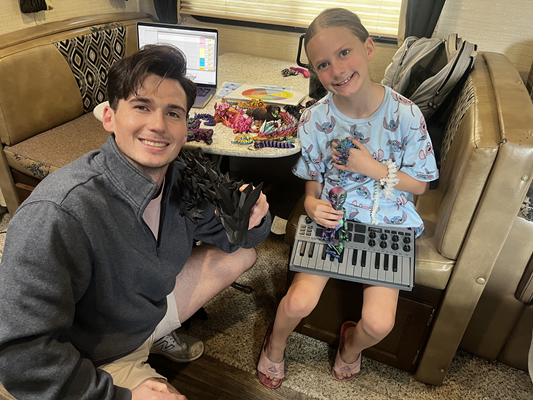 A man and a young girl with a small piano keyboard in her lap smile at the camera.