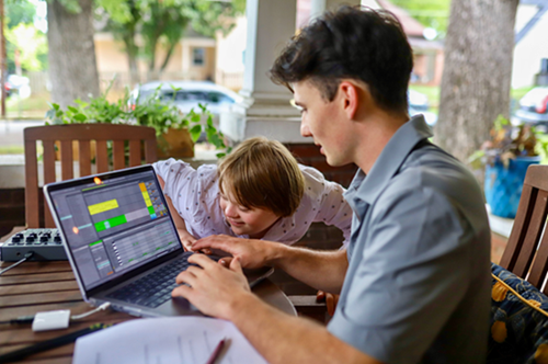 A man and a boy look intently at a laptop screen.