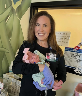 An occupational therapist holds a sleeping baby.